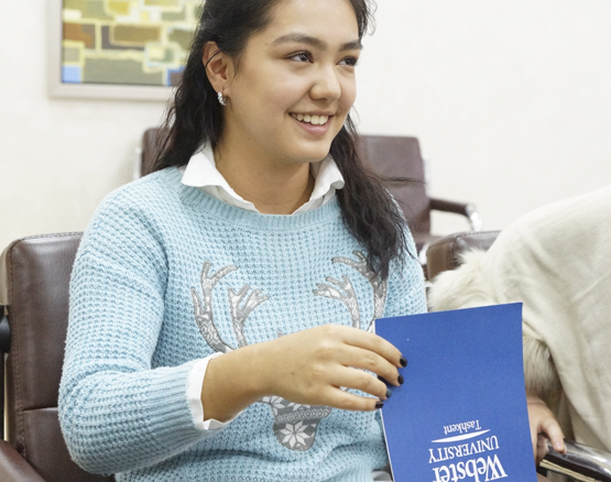student flips through Webster Tashkent brochure