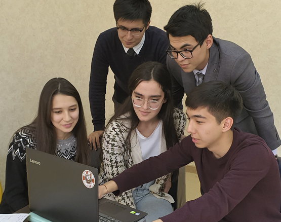 group of students huddled around to look at laptop