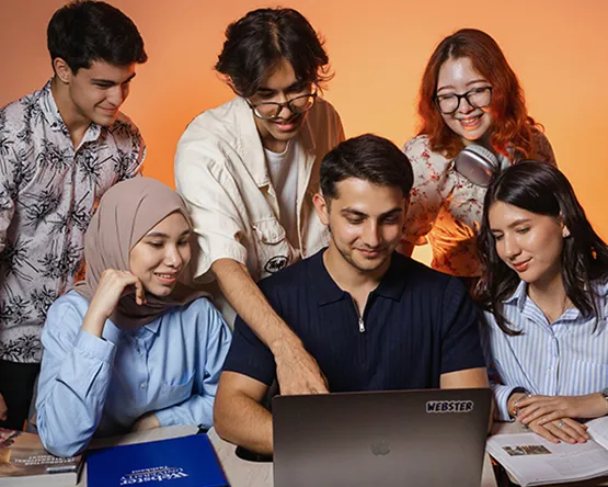 Six students group together in front of laptop.