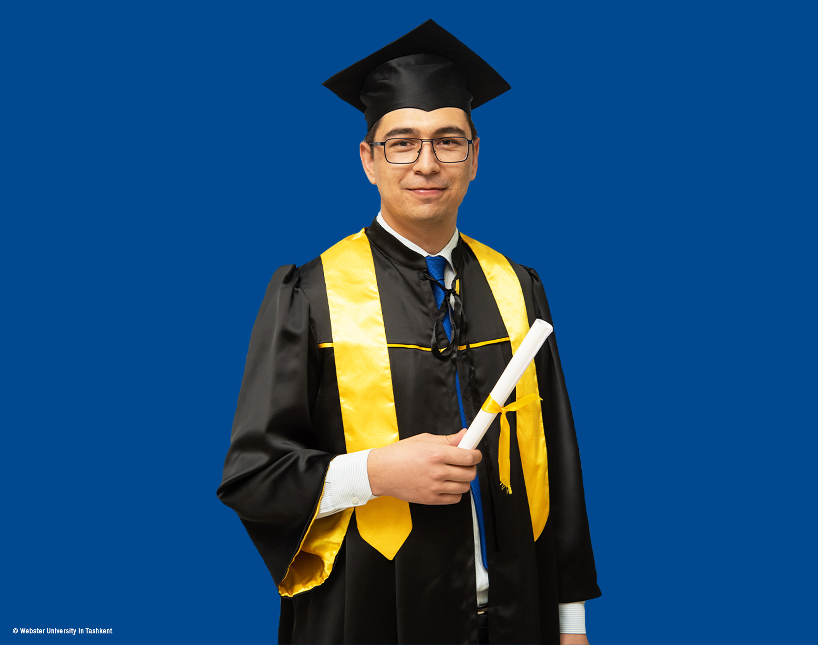 MBA Alumnus Ibrokhimkhon Akhmadkhonov in his commencement gown looks into the camera