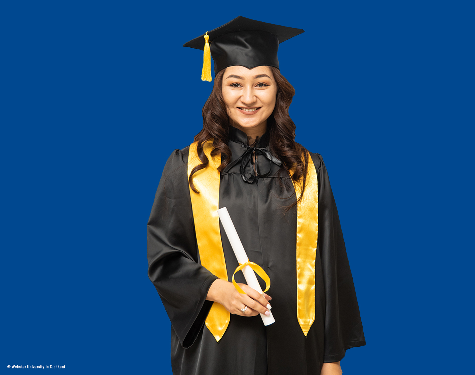 MBA Alumna Tursunoy Usmnonova looks into the camera in her commencement gown