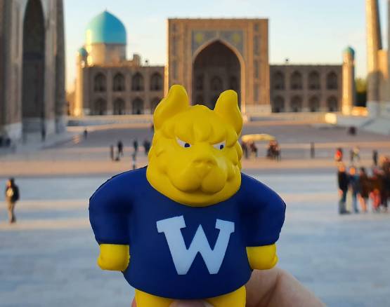 A Gorlok figurine held up infront of the Kalyan Minaret landmark.
